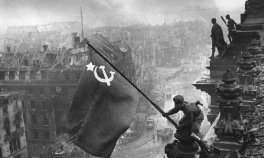 Imaginea emblematică a căderii Berlinului: un rus, cu două ceasuri la mână, ridică steagul Armatei Roșii deasupra Reichstag-ului